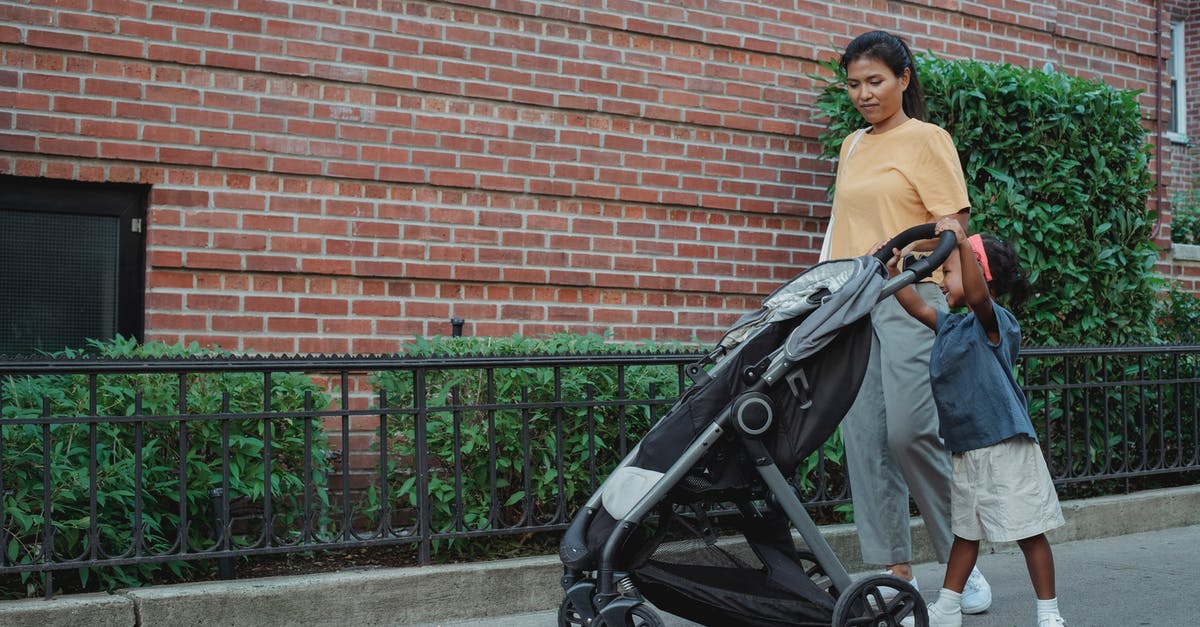 Carry Stroller on Emirates flight without a kid? - Full length of Asian mom with small girl strolling on footpath with stroller near green hedge in city