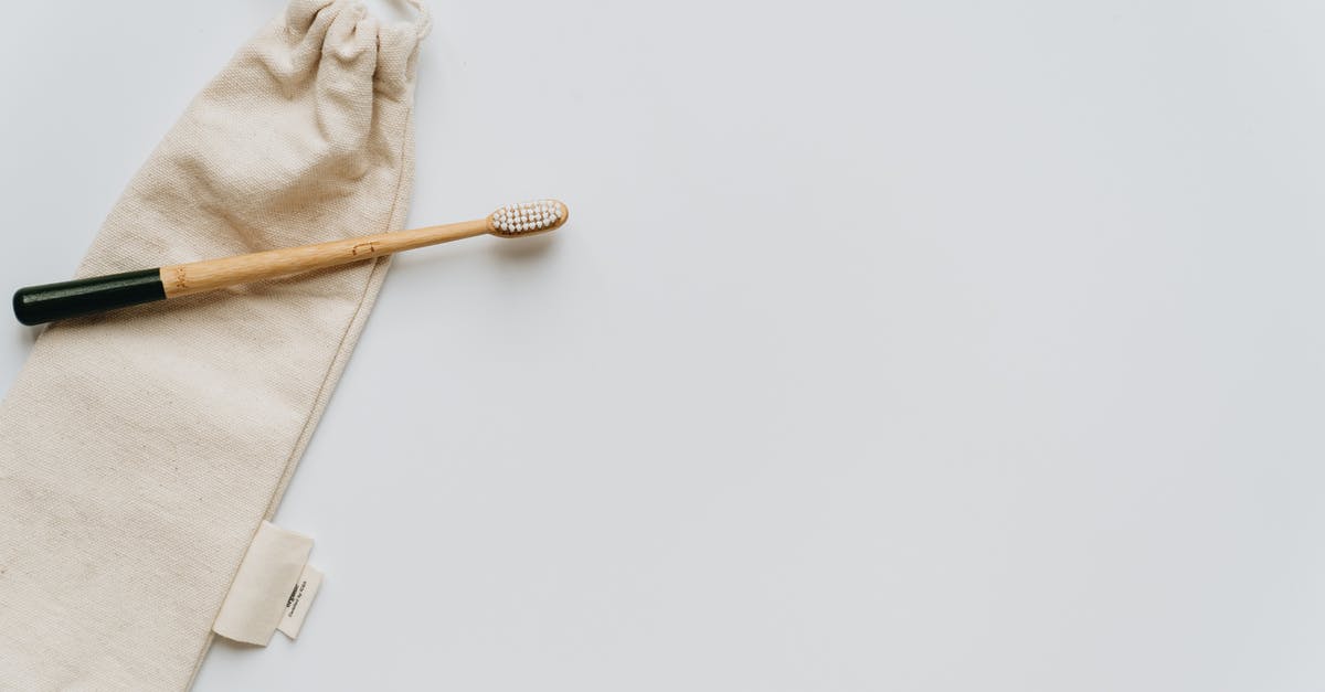 Carry-on liquids in toiletry bag (not clear ziplock)? - Top view of beige fabric crumpled bag with ties and clean wooden toothbrush on white background with smooth surface