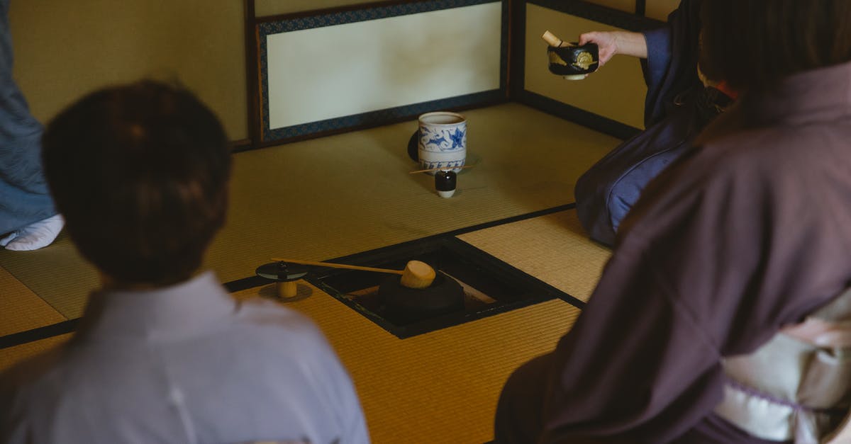 Cast iron pot in cabin luggage? - Anonymous group of people wearing authentic robe sitting near bamboo ladle on iron pot and dishware for traditional Japanese ceremony