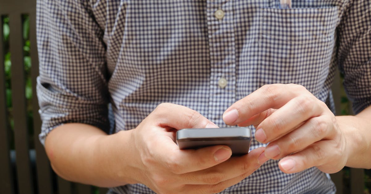 Cell phone frequencies in Nicaragua [duplicate] - Man in Plaid Shirt Using Smartphone