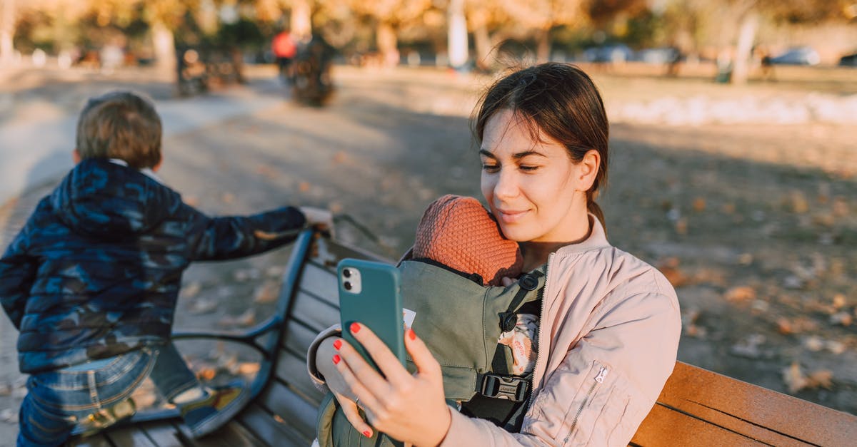 Cellphone carriers in Europe - A Woman Sitting on a Wooden Bench at the Park while Using Her Mobile Phone