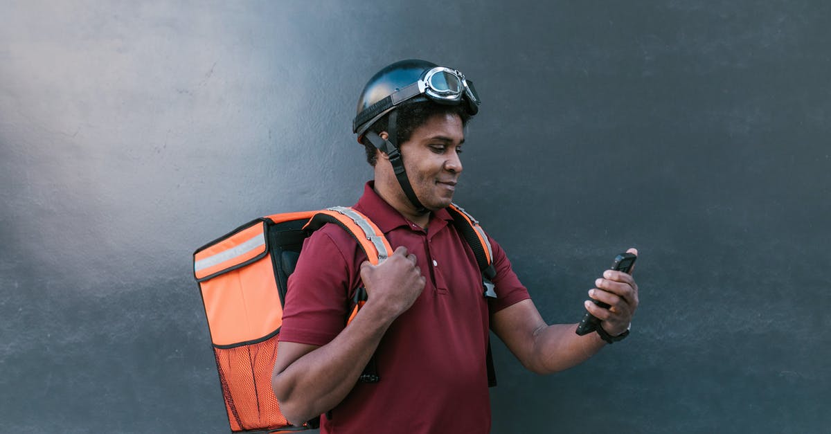 Cellphone service in Southeast Asia? - Man in Red Polo Shirt Wearing Helmet Holding Black and Gray Smartphone