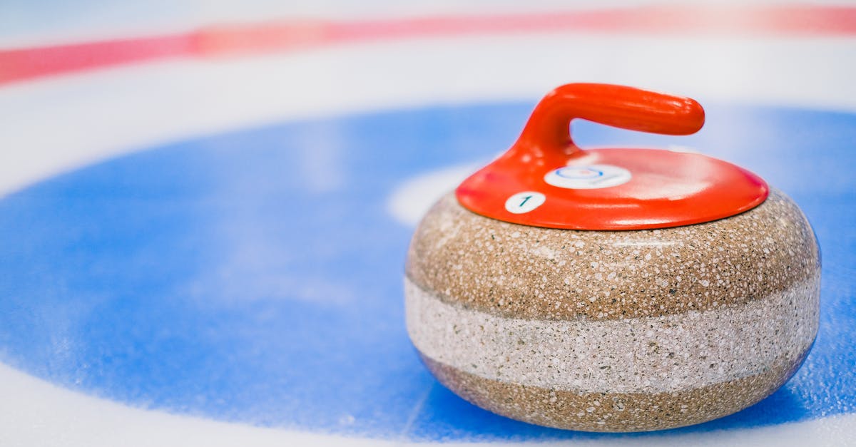 Chaining same day round trips - Round curling stone with red handle placed on ice surface on ice rink in daytime