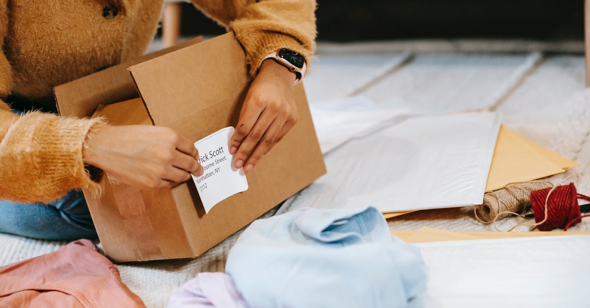 Change of mailing address - Crop unrecognizable woman sticking shipping label on parcel