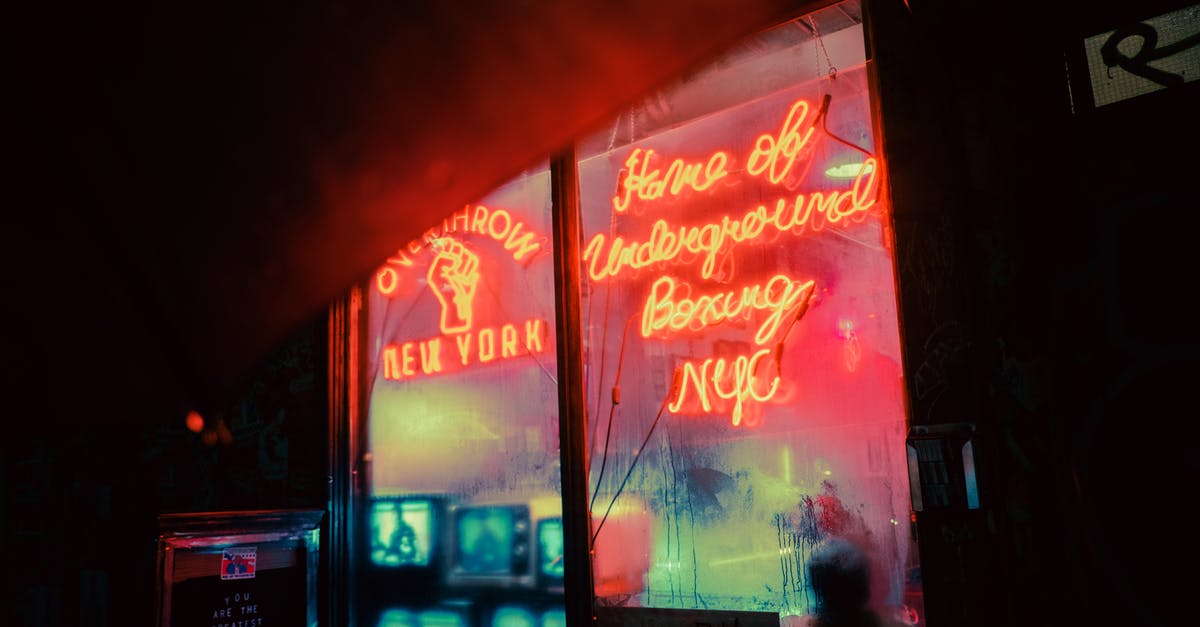 Changing money at Antalya airport, Turkey, late at night - Exterior of shop with shiny neon inscriptions and vintage TV sets on street in late evening