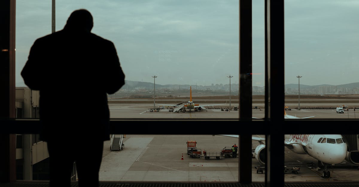 Changing planes in Athens - Silhouette of Person Standing Near Glass Windows