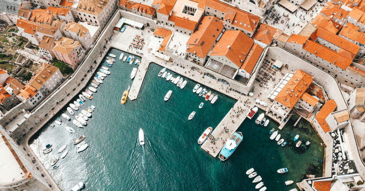 Chania port to Chania city - Breathtaking drone view of coastal town with traditional red roofed buildings and harbor with moored boats in Croatia