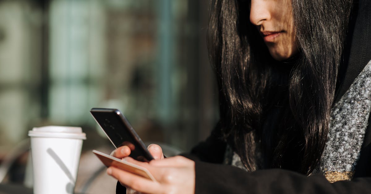 Charges when using a Euro country debit card in Budapest - Crop ethnic shopper making purchase on smartphone with debit card