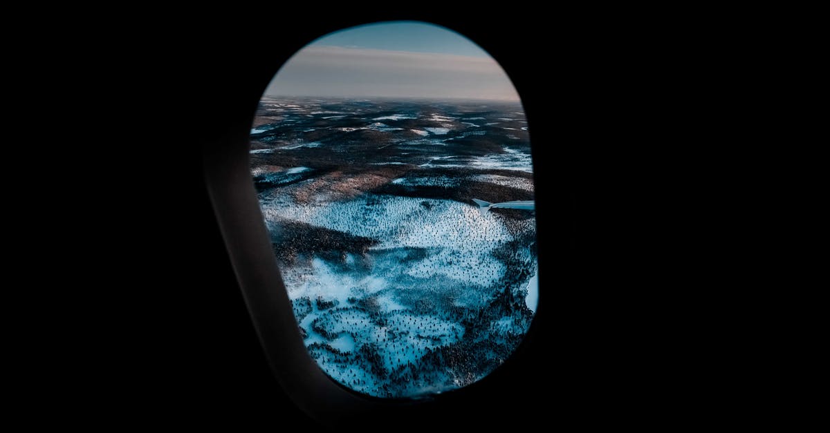 cheap air travel tickets through blind company - Through aircraft window of picturesque mountainous valley covered with snow under cloudy sunset sky