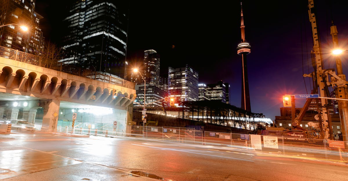 Cheap but comfortable way to get from Kingston, ON, Canada to Toronto? - Cityscape with empty road near bridge and modern multistory buildings and CN tower located on dark street with glowing lights