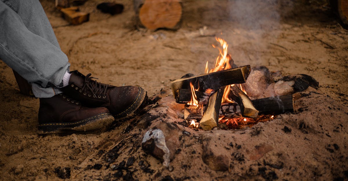 Cheap camping in southern Brazil - Burning Campfire and Feet of a Person in Hiking Boots