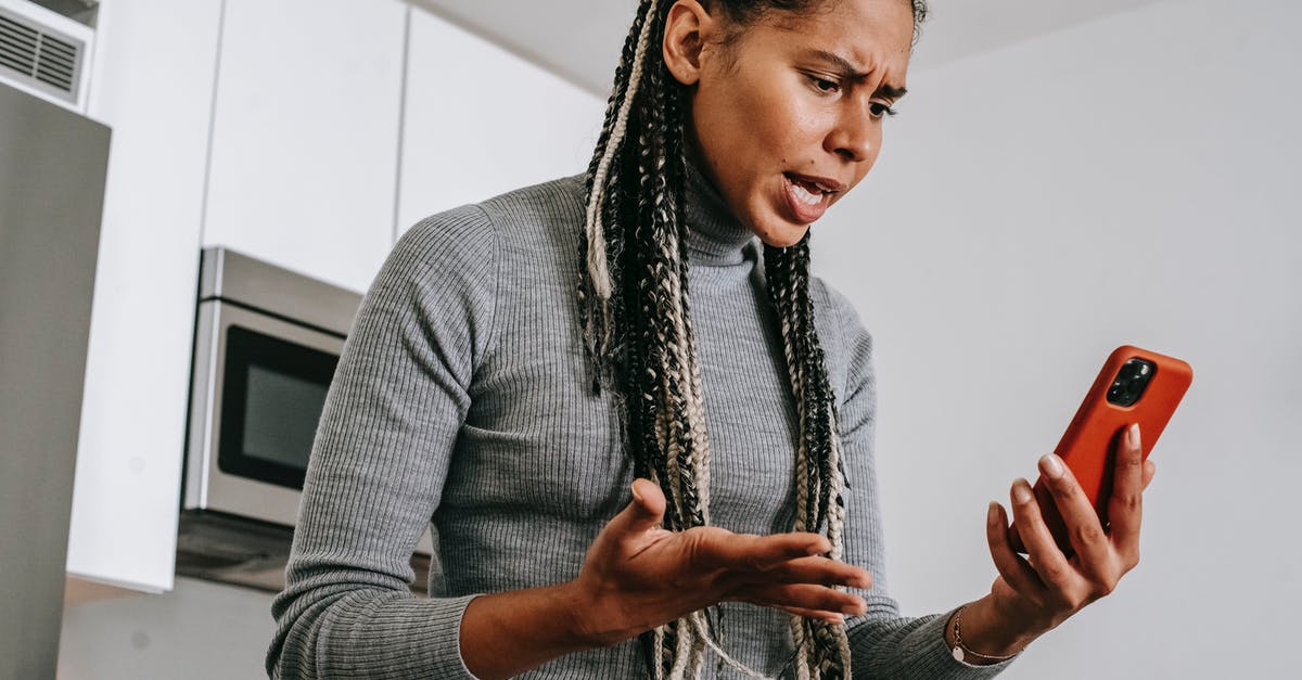 Cheap phone calls from Canada to Poland - Annoyed black woman having video chat on smartphone at home