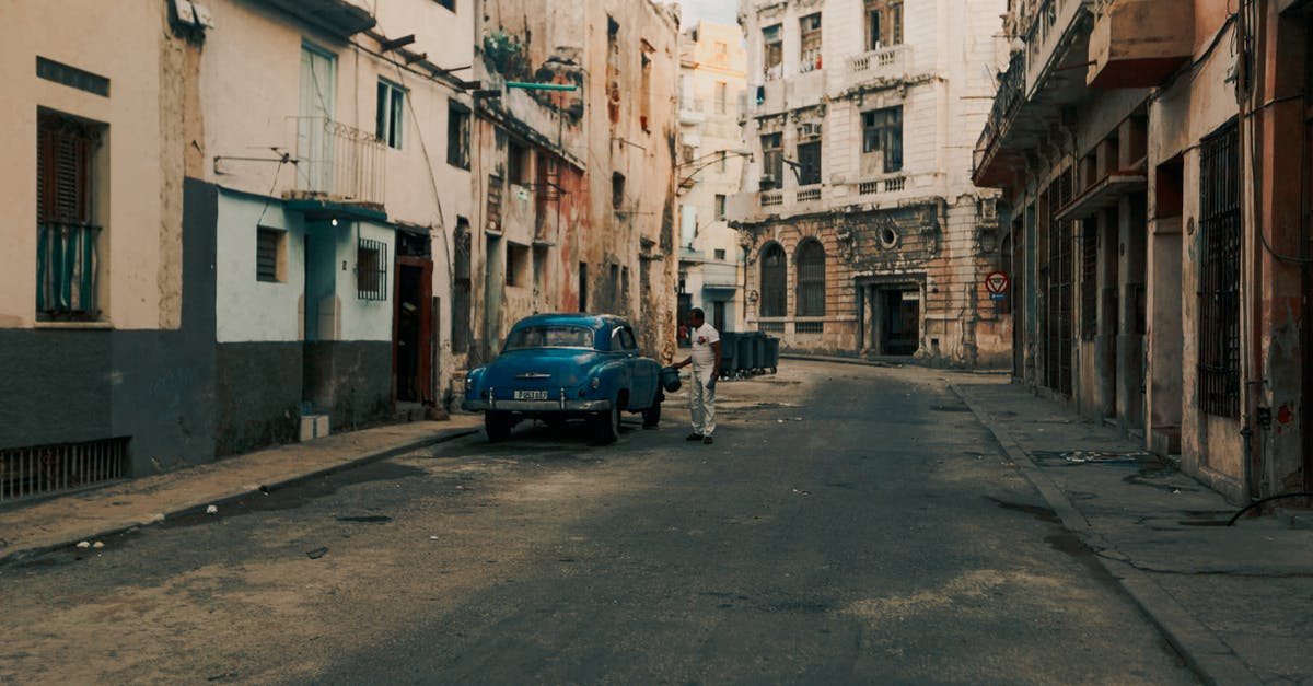 Cheap places to park a car in Barcelona? - Owner standing beside a Parked Car in an Old Street 