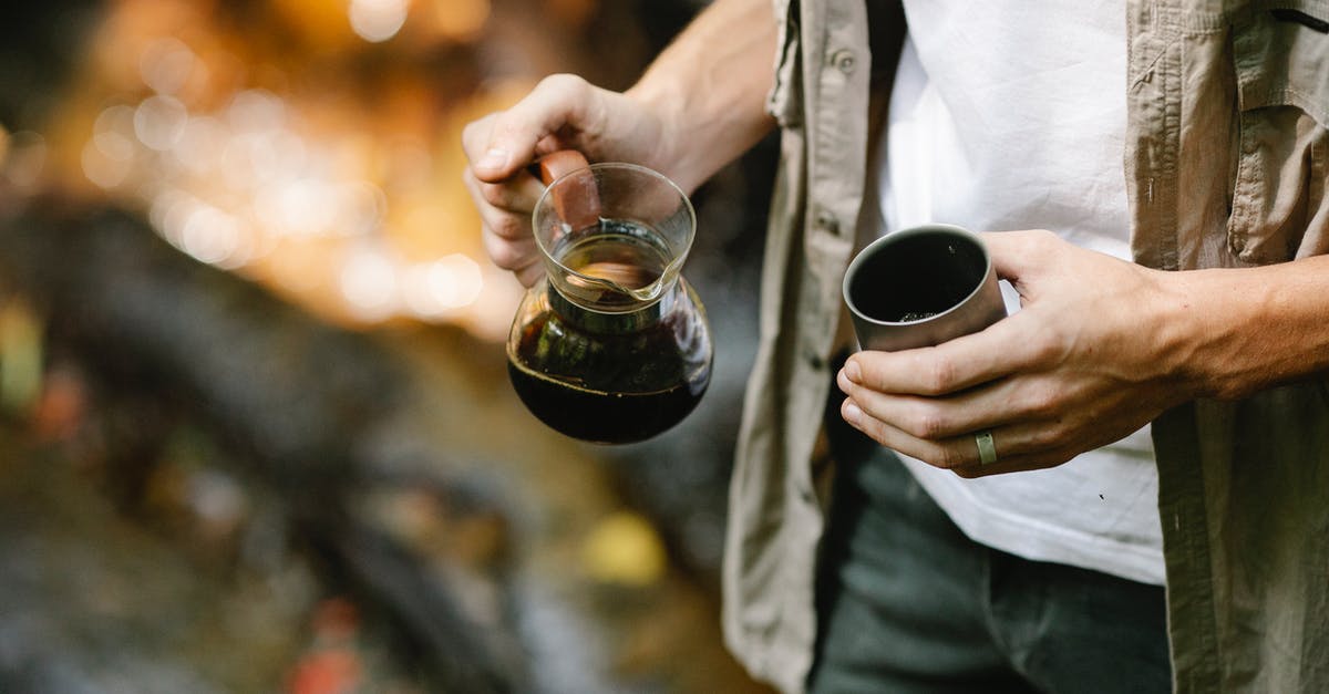 Cheaper alternatives to travel to Hokkaido? - Crop anonymous male camper pouring freshly brewed coffee from chemex coffeemaker into metal mug while resting in autumn forest during trekking