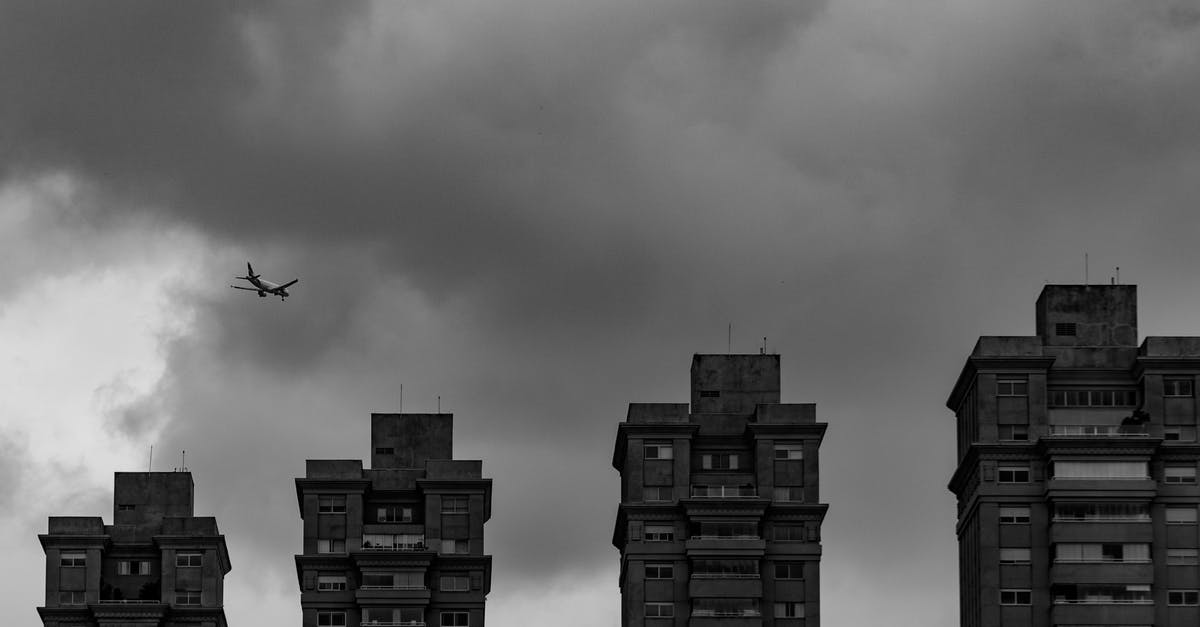 Cheapest flight "from any city" - Aircraft flying in thick clouds above city buildings