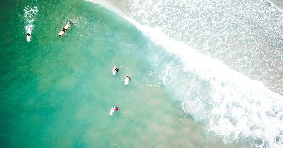 Cheapest ride from Raja Ferry to Chaweng Beach [closed] - Picturesque drone view of unrecognizable people riding waves on surfboards in powerful turquoise ocean with sandy beach