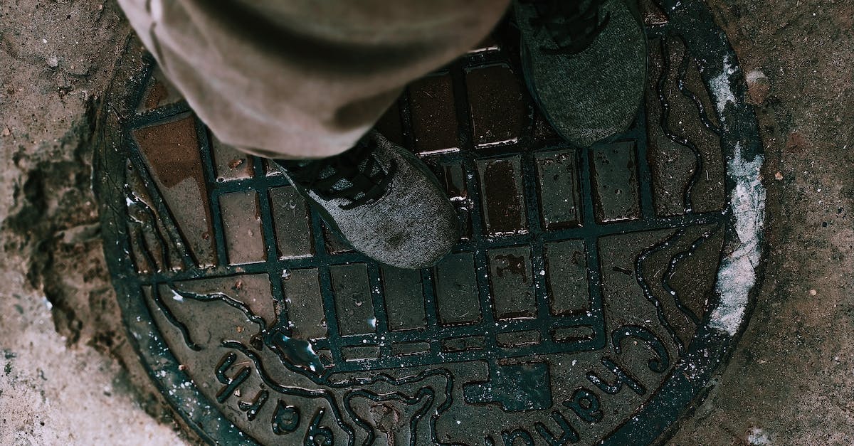 Cheapest way to get HON circle status? - From above anonymous person in boots and pants standing on shabby metal manhole lid on city street