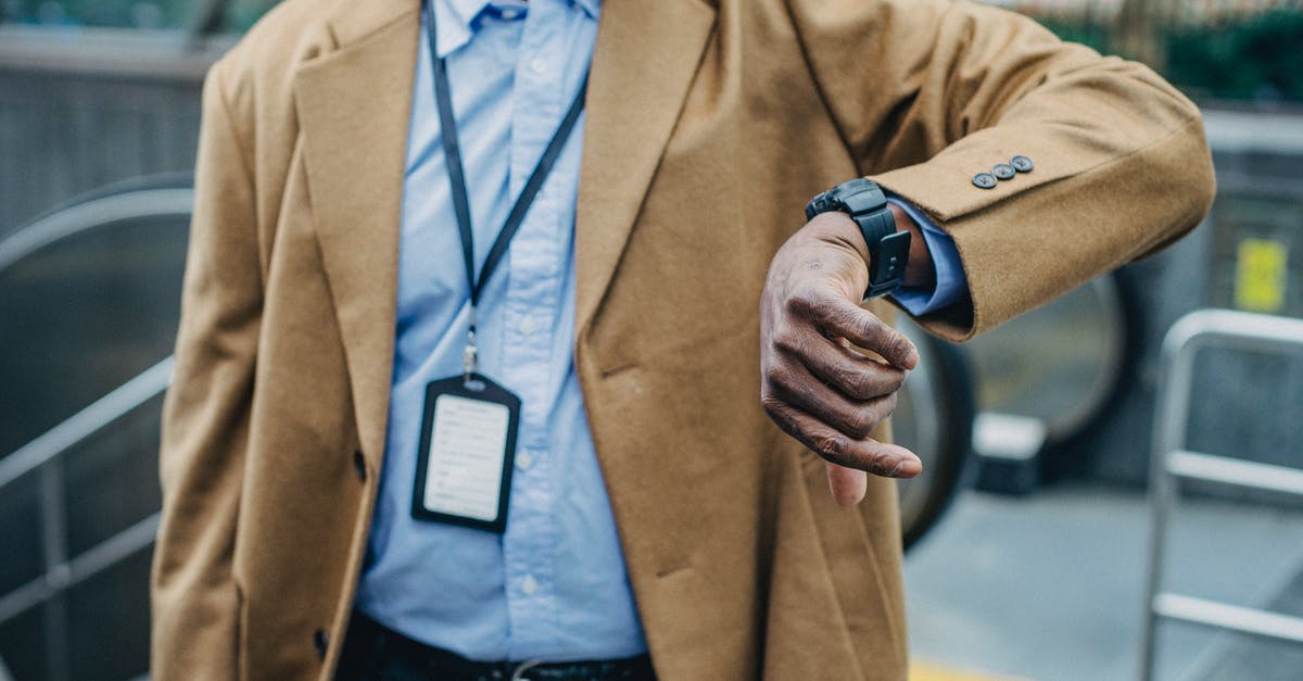 Checked baggage through TSA carry-on security when late for check-in? - Crop anonymous African American businessman in elegant formal suit looking at wristwatch while standing near metro entrance