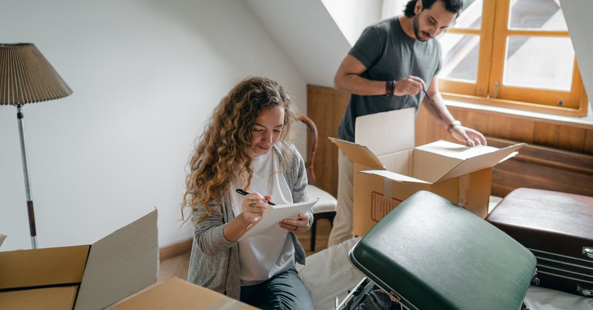 Checked cardboard box - Couple packing belongings into suitcases and carton boxes