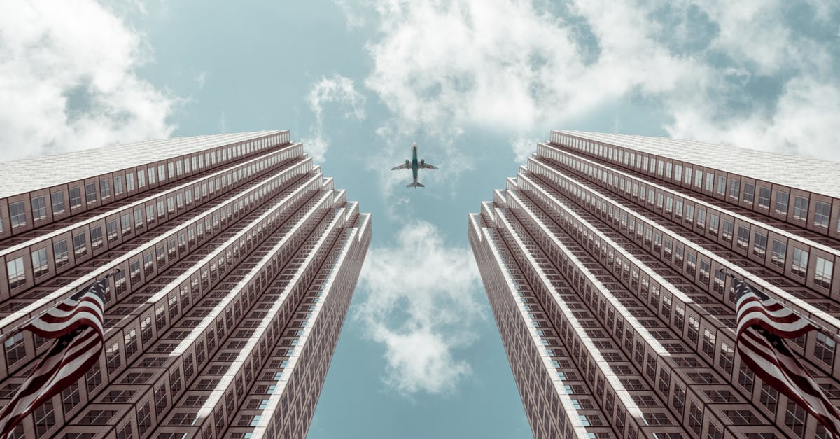 Check-in when flying as a minor? (American) - Worm's-eye view Photo of Plane Between Two High-rise Buildings