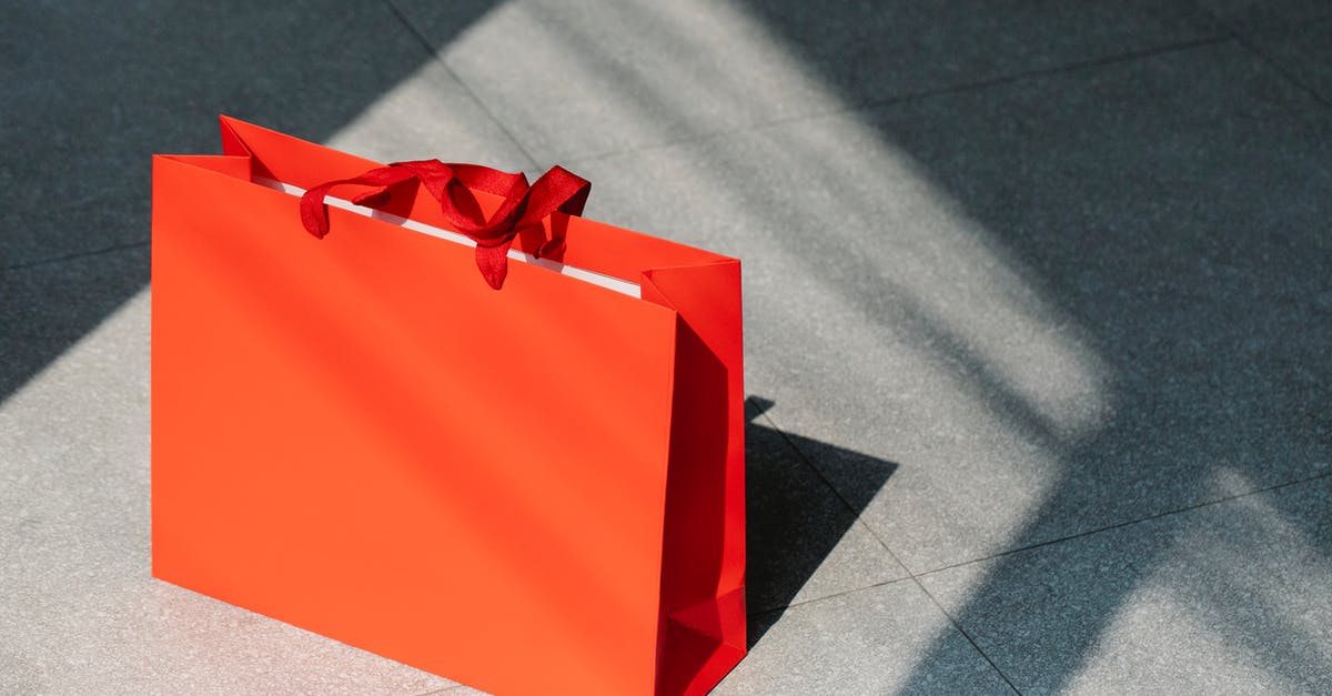 Checking in a new bag during a layover - Red paper shopping bag on gray ground