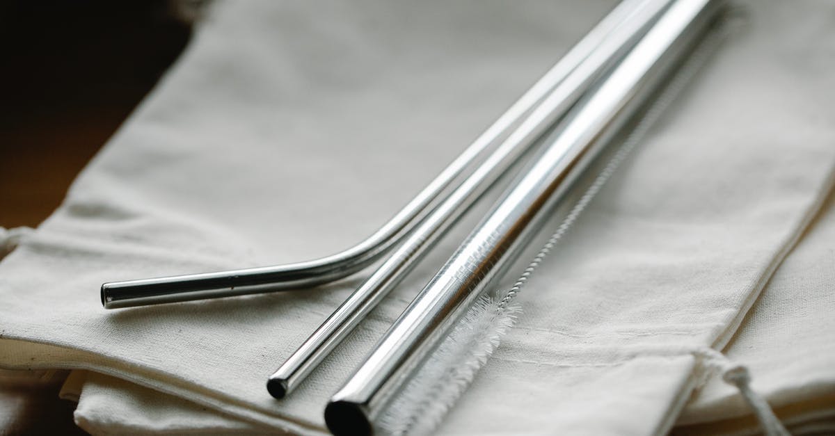 Checking in a new bag during a layover - Collection of stainless steel straight and bent straws placed on reusable bags on table