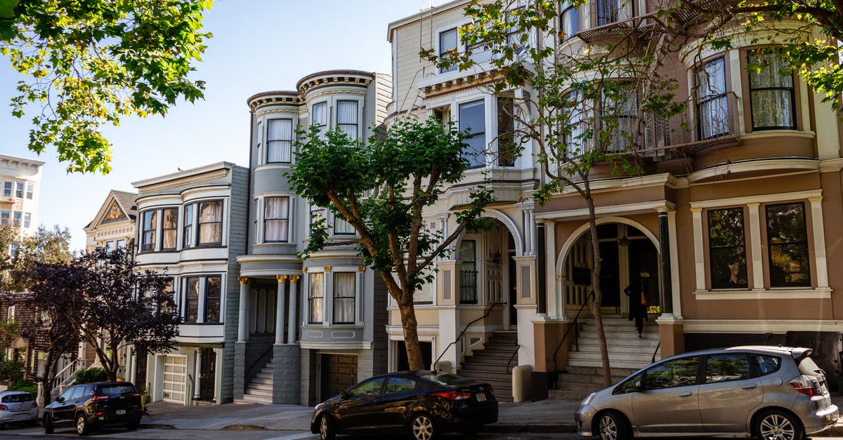 Checking in baggage early with United Airlines at San Francisco - Cars parked near mansions in city residential district in sunlight