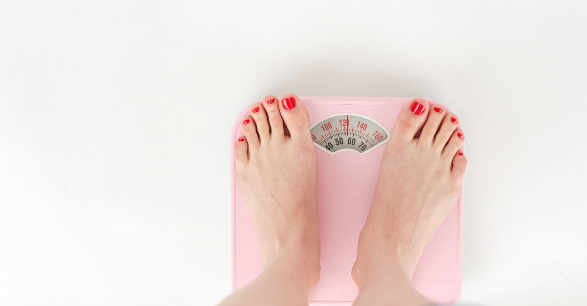 Checking MetroCard balance outside? - Top view of crop anonymous barefoot female measuring weight on scales on white background