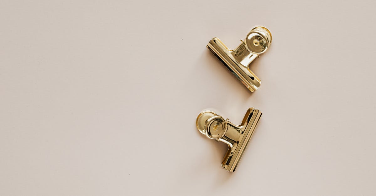 Checking small items on a plane? - Golden metal clips on beige background