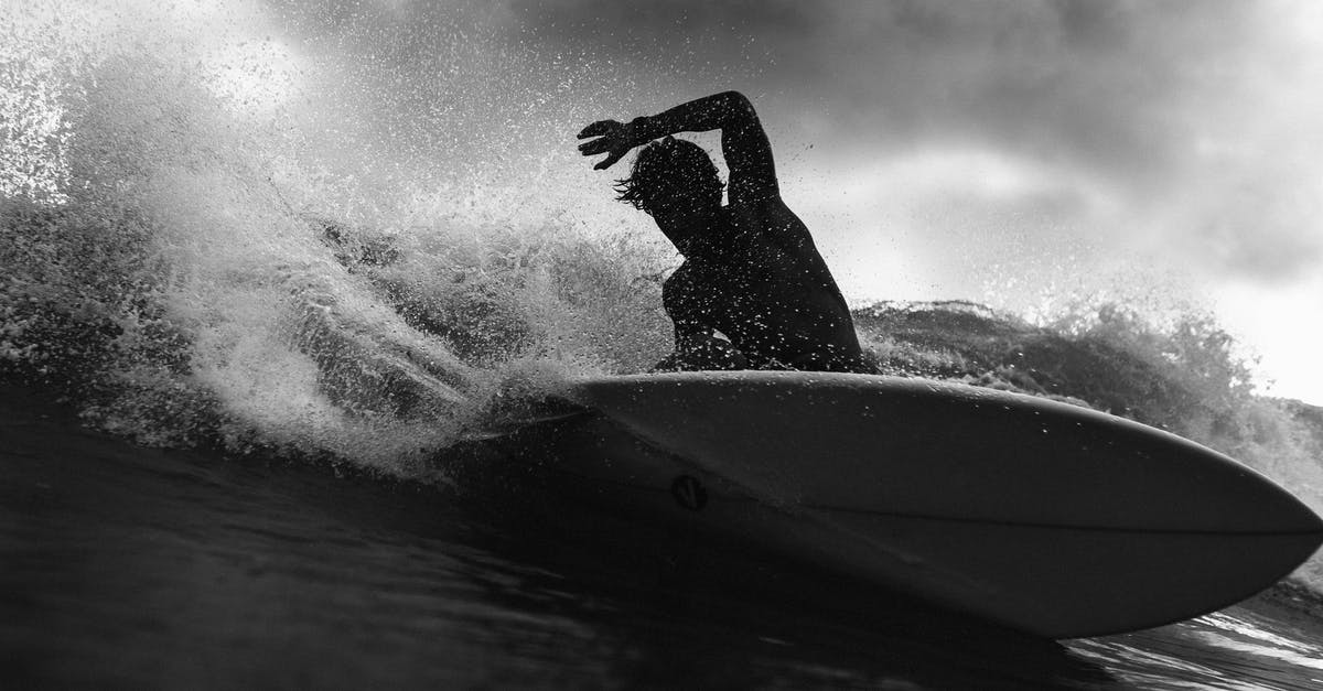Chicago's summertime weather [closed] - Black and white of anonymous male surfer riding on wave with raised arm against cloudy sky in stormy weather outside