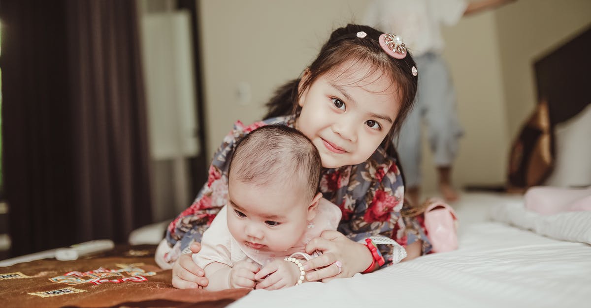 Child born in Russia needs an exit visa? - Happy Asian girl child embracing newborn baby lying on bed