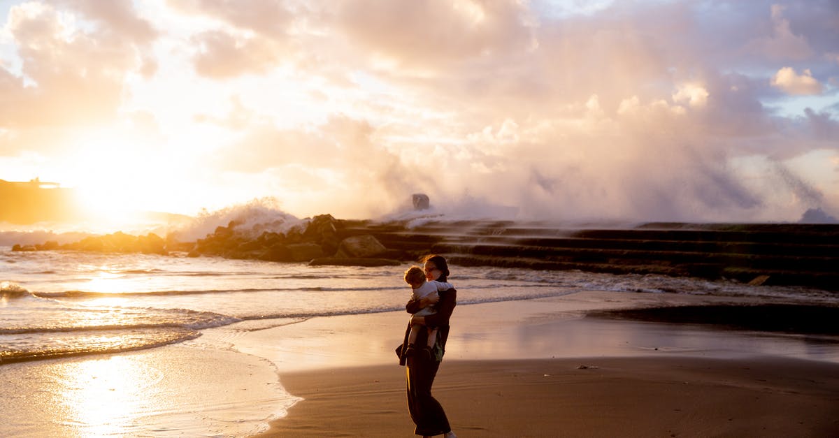 Child travel consent for Lima, Peru - Woman Standing on Seashore Carrying Her Child during Sunset