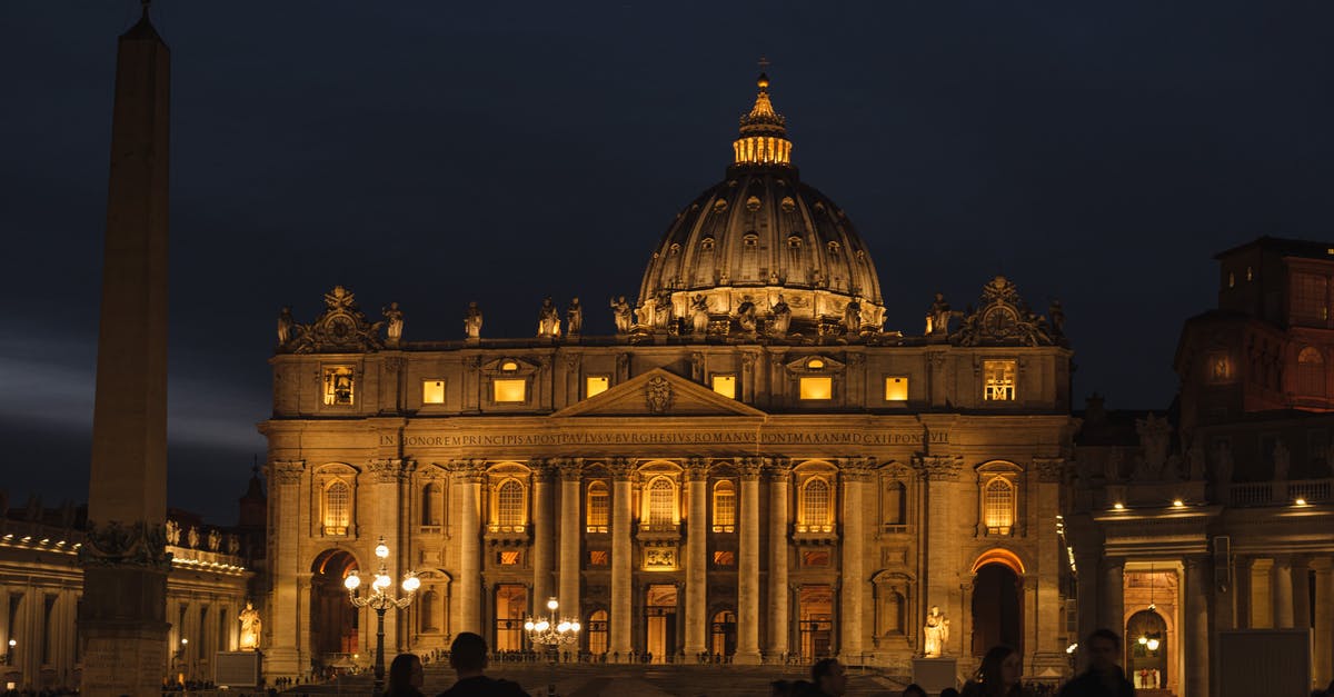 Chilean citizen travelling to Europe (part 1: Italy connection) - Old stone church with sculptures and columns against anonymous people at dusk in Vatican City Italy