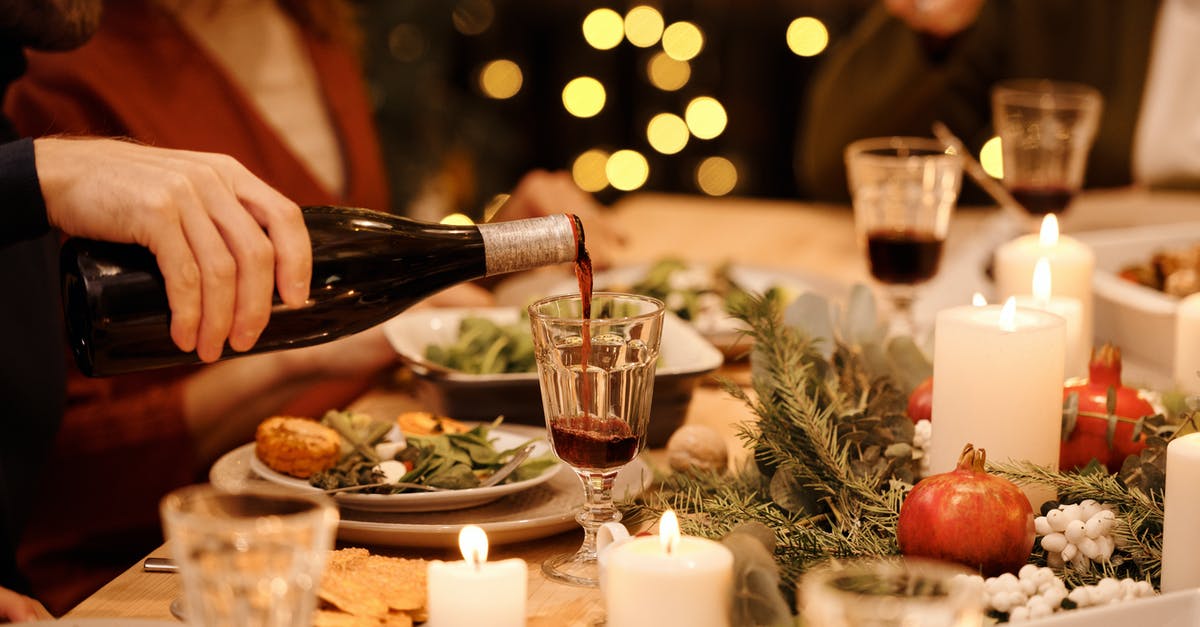 Christmas Dinner in Foreign Country - Person Pouring Wine on Glass