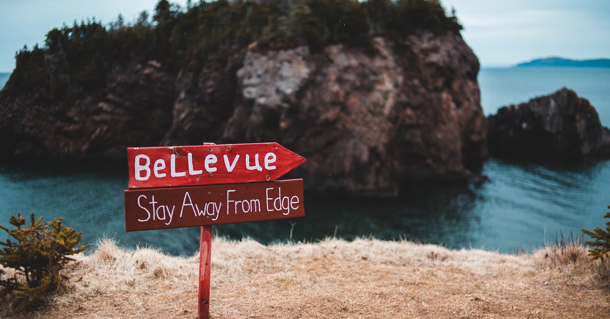 Circular signs with blue edges - Warning sign on edge of rocky cliff