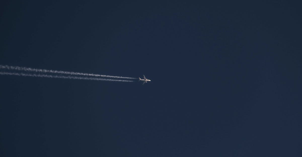 Clearing TSA at JFK for international flight - From below of modern distant airplane flying high in air over clear cloudless blue sky with white trace on sunny day