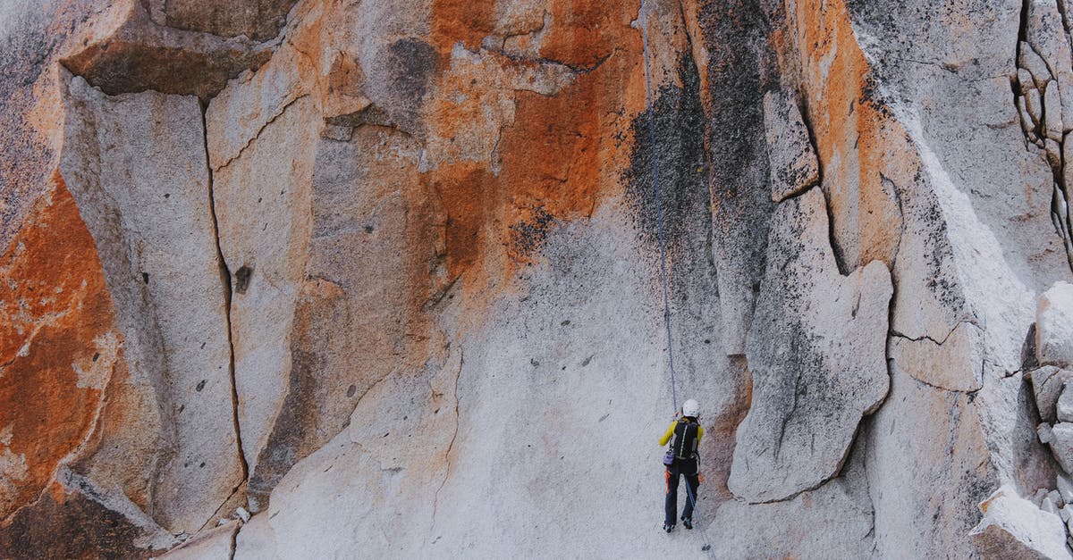 Climbing Mount Aragats in October - From below back view of anonymous climber in equipment with backpack ascending bright shabby mount while practicing extreme sport