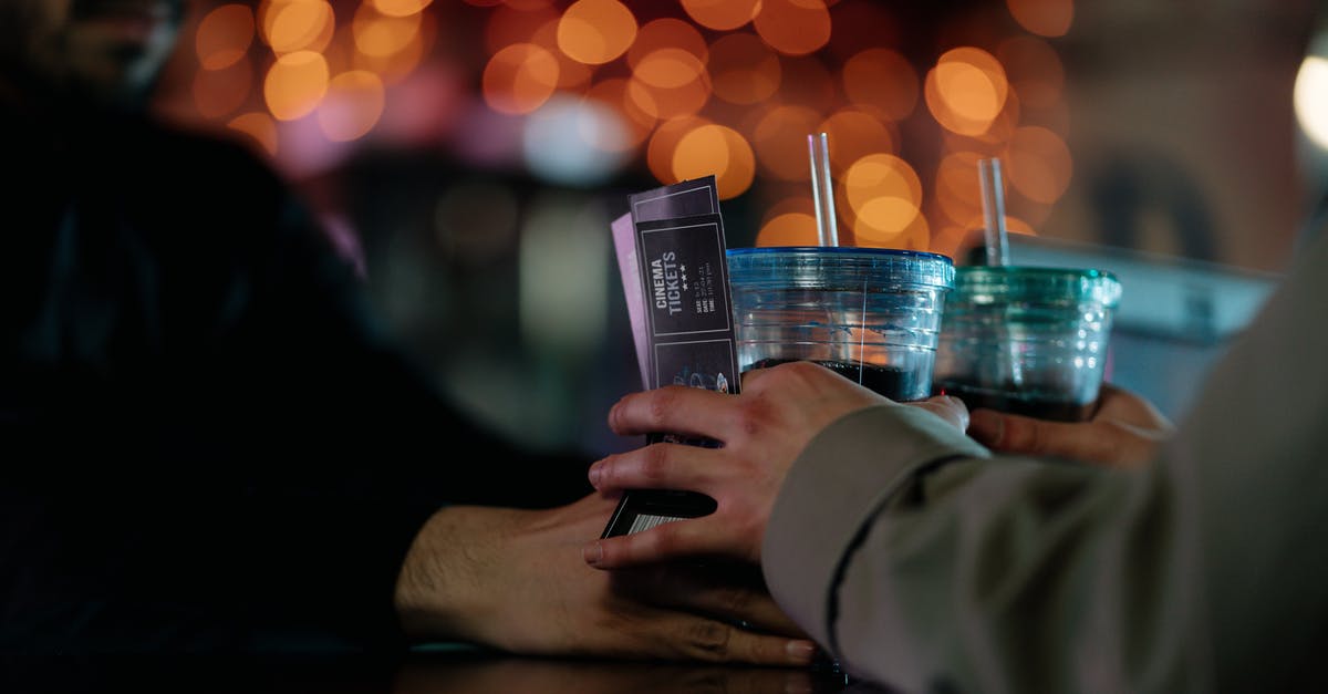 Combining 2 roundtrip tickets - A Bearded Man Handing Out a Couple of Drinks to a Person Holding Cinema Tickets