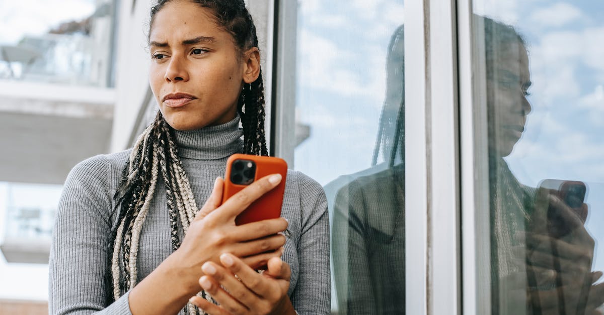 Commuting from Frankfurt to Bad Homburg - Low angle of concerned ethnic female with smartphone in stressful situation near glass wall