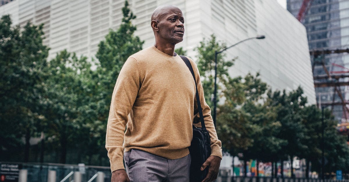 Commuting options from Madrid city center to Leganes campus - From below of adult African American businessman with personal bag walking in city center