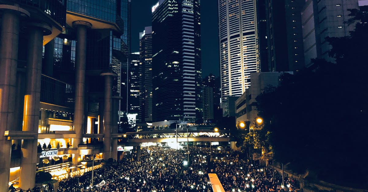 Commuting options from Madrid city center to Leganes campus - From above of crowd of people standing on street in dark modern city centre during mass protest