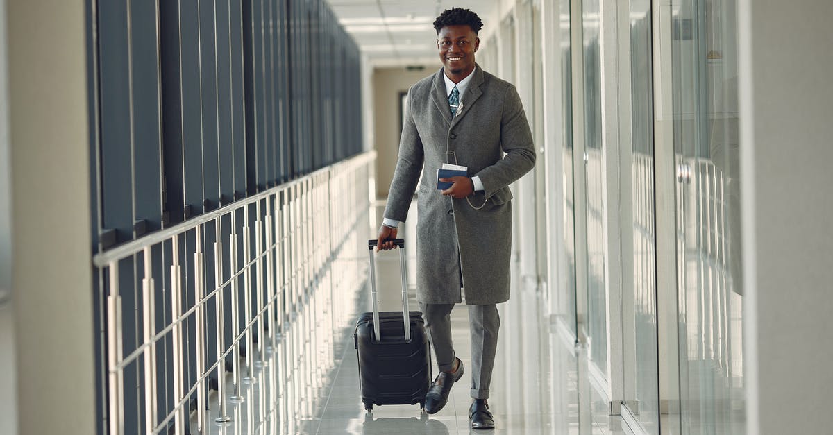 Compensation for delayed baggage on international United flight - Stylish man with suitcase and passport walking along airport corridor