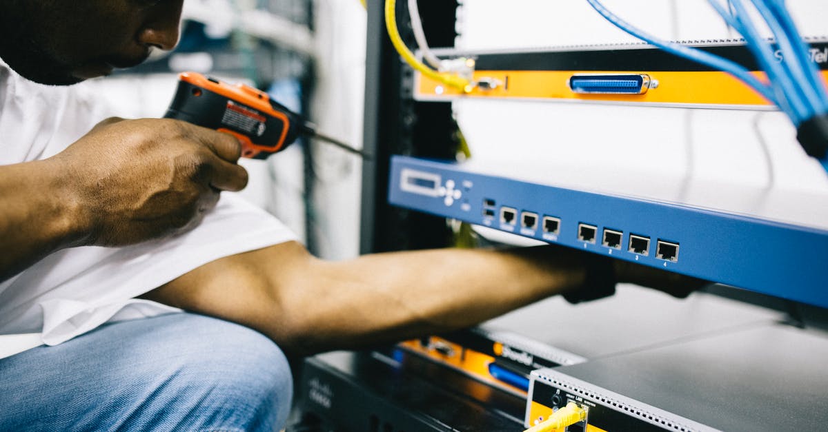 Concerns regarding UK Border Control and no job - Side view crop concentrate African American male mechanic in jeans and white shirt using screw gun while working with hardware