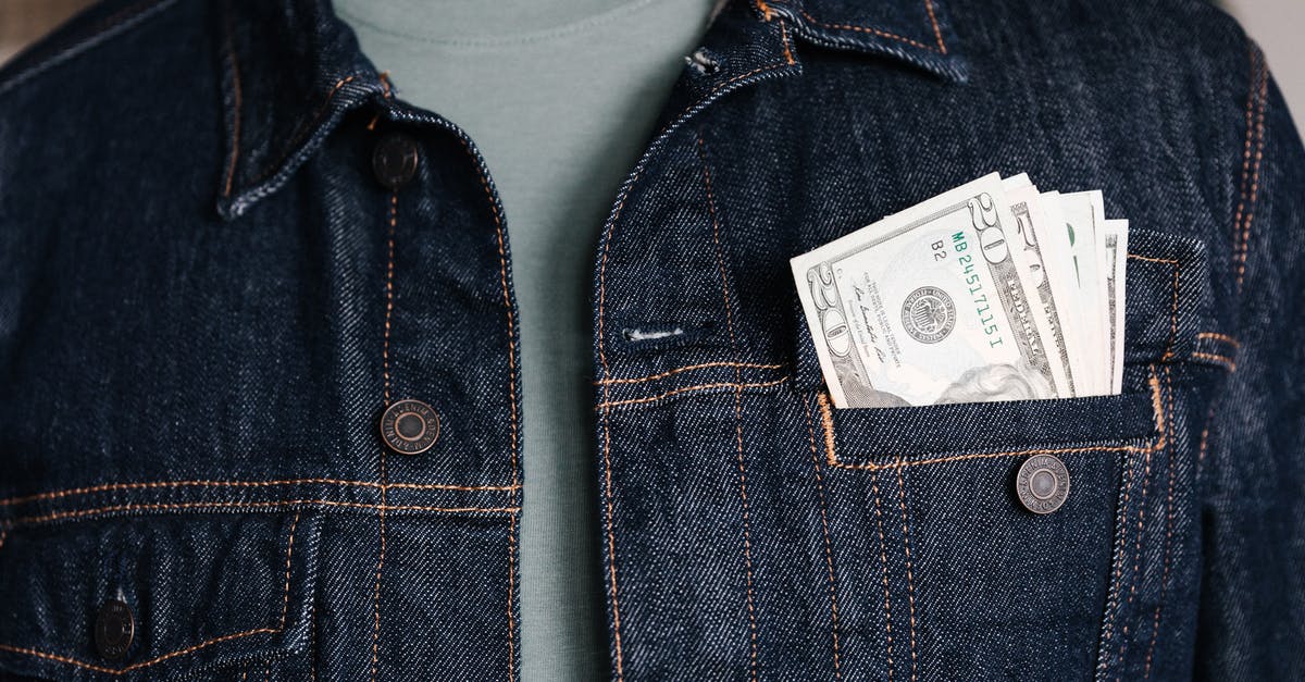 Connecting flight inside the U.S then Canada - Crop unrecognizable male in casual outfit standing with different nominal pars of dollar banknotes in pocket of jeans jacket
