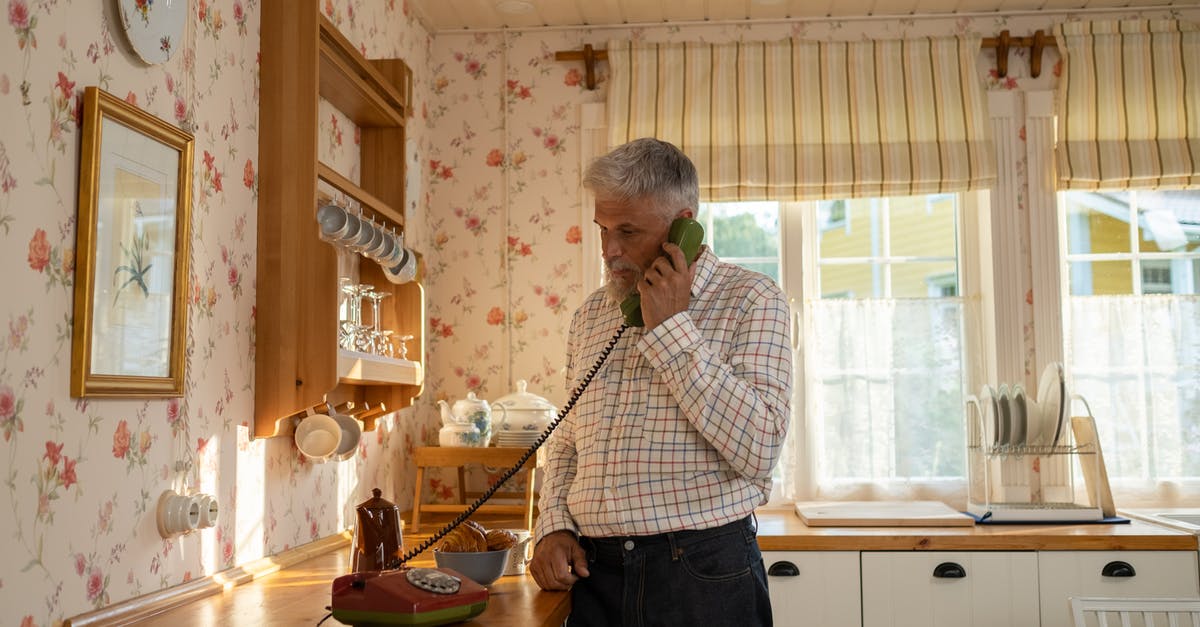 Connecting flights (domestic) on separate tickets with no checked baggage - Senior Man Talking on Landline Phone in Old-Fashioned Kitchen