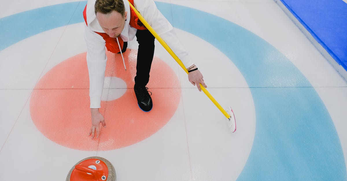 Connecting from ICE to regional trains (Deutsche Bahn) - From above of concentrated sportsman in activewear throwing stone during curling competition on ice rink in daytime