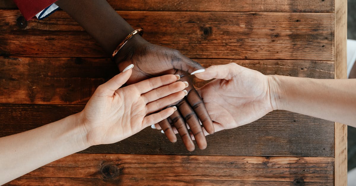 Connecting in Amsterdam with different airlines - Diverse women stacking hands on wooden table