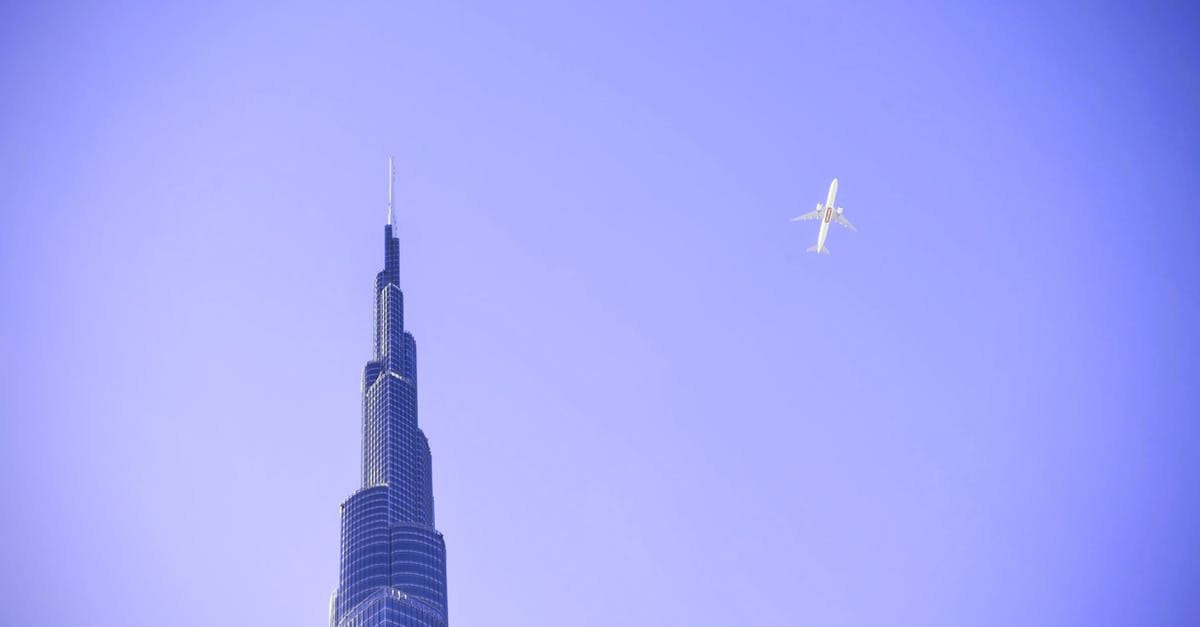 Connecting in Dubai on different airlines - White Airplane Flying over Building