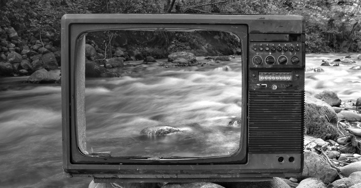 Connecting through Chicago O'Hare - Black and white vintage old broken TV placed on stones near wild river flowing through forest