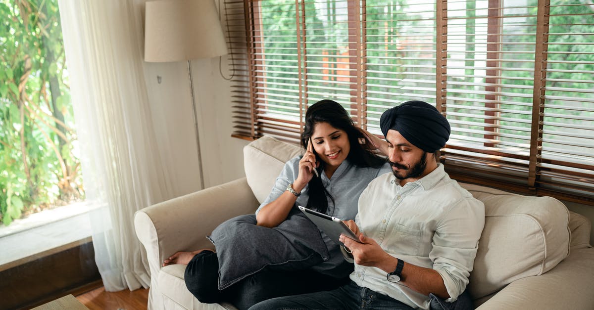 Converting Chinese spouse visa to work visa [closed] - Young Indian man browsing tablet while woman talking on smartphone on couch